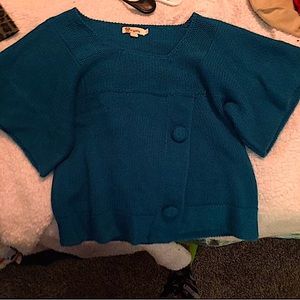 Crop-top blue knitted sweater, with decorative buttons.